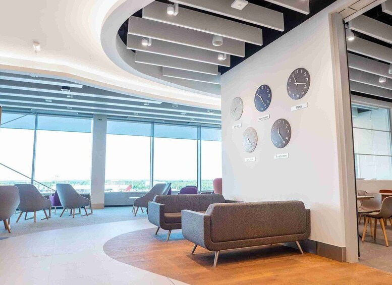 A modern office interior with a curved ceiling, multiple clocks displaying different city times, and a seating area with chairs and a sofa. 3