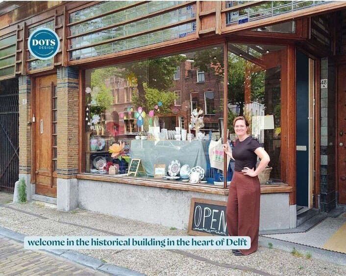 A historical building in the heart of Delft with a shop window displaying ceramics and a sign reading 'OPEN'. 2