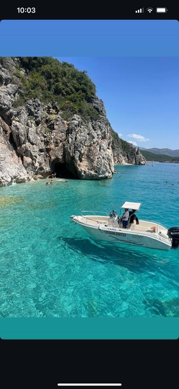 A boat named 'Vaso' with 'RENT' written on it, floating in clear turquoise water near rocky cliffs. 5