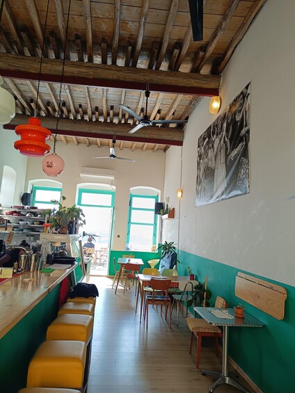 A rustic cafe interior with wooden beams, a bar area, and colorful seating. 2
