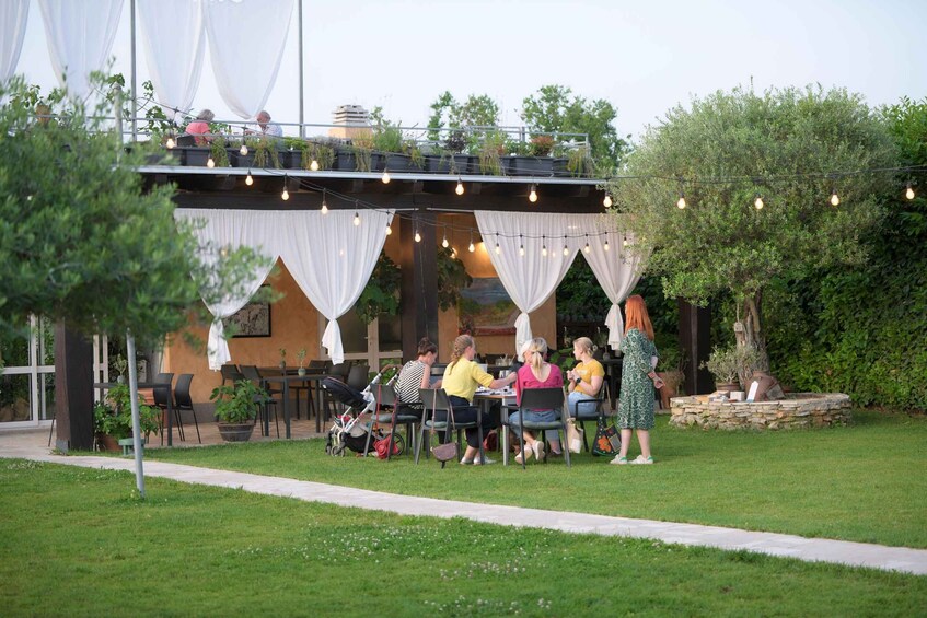 An outdoor patio with tables and chairs, surrounded by greenery and string lights. 4