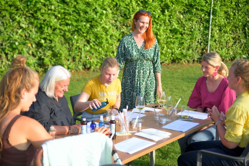 A group of people sitting around a table outdoors with a hedge in the background. 5