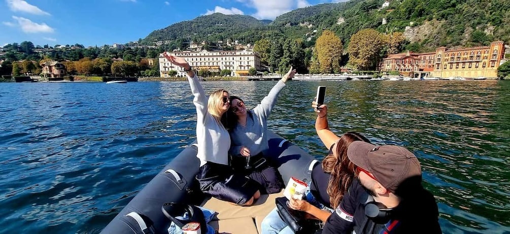 A boat on a lake with people on board, a mountainous landscape in the background, and buildings along the shore. 4