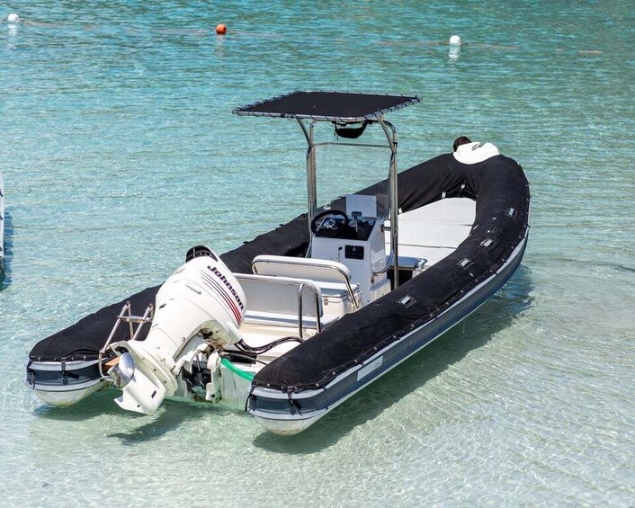 A small motorboat with a canopy, floating on clear turquoise water. 2
