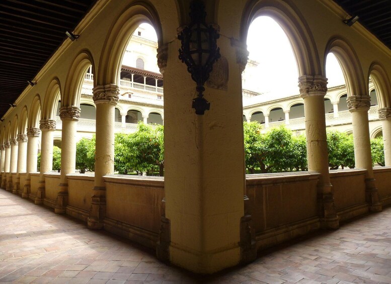 A courtyard with arches, columns, and a building in the background. 1