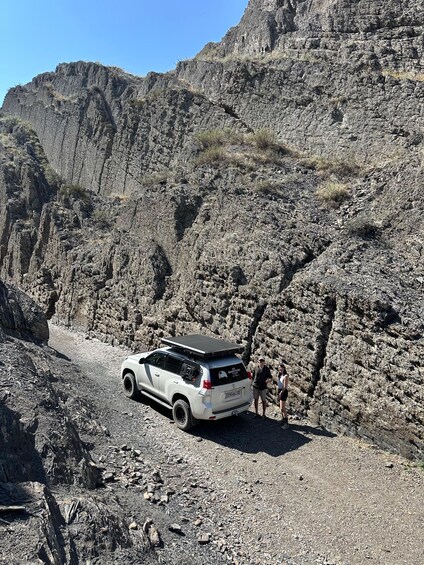 A white SUV parked on a rocky trail with a mountainous backdrop. 3