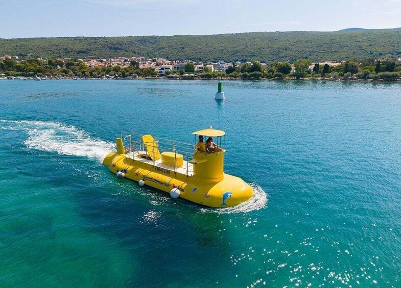 A yellow submarine-like boat with people on board, floating on a clear blue lake with a town in the background. 4