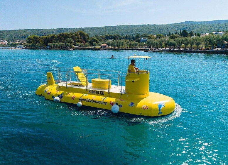 A yellow semi-submarine with a person on top, floating on clear blue water. 1