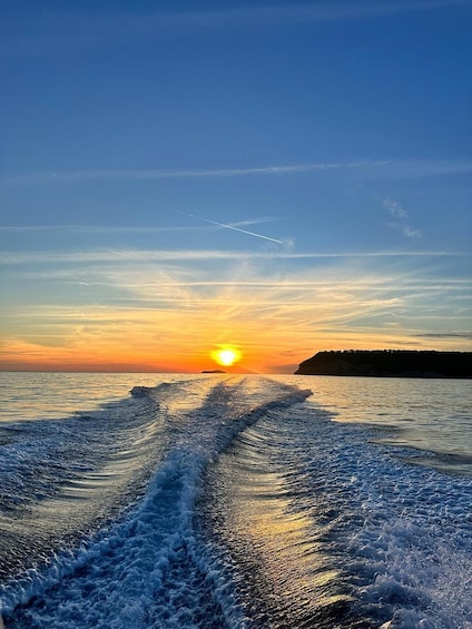 A sunset over the ocean with a boat's wake and a clear sky. 3
