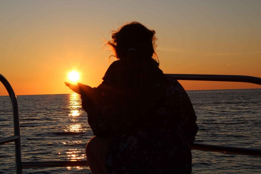 A silhouette of a person holding a camera, facing the sunset over the ocean. 1