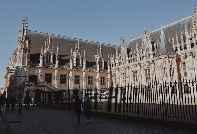 A historic building with ornate Gothic architecture, a paved courtyard, and a black metal fence. 5