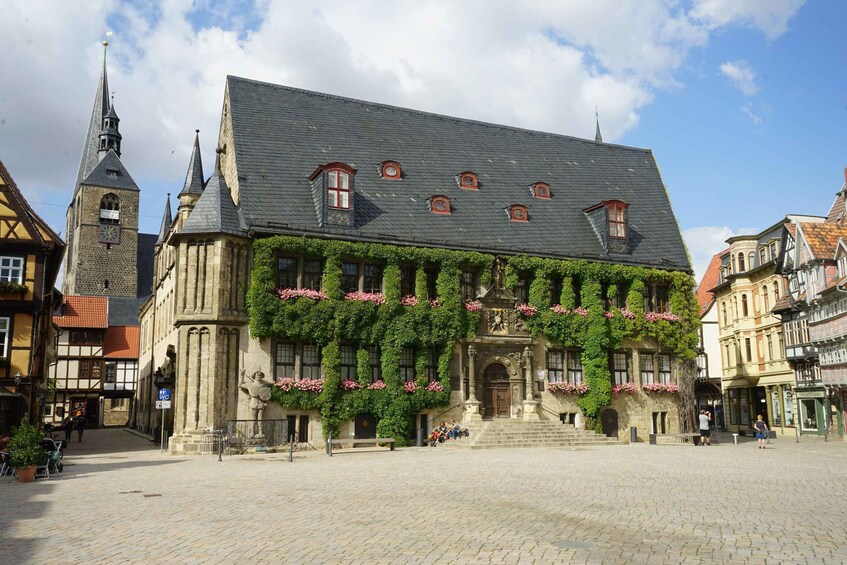A historic building with a steeply pitched roof, a clock tower, and ivy-covered walls. 5