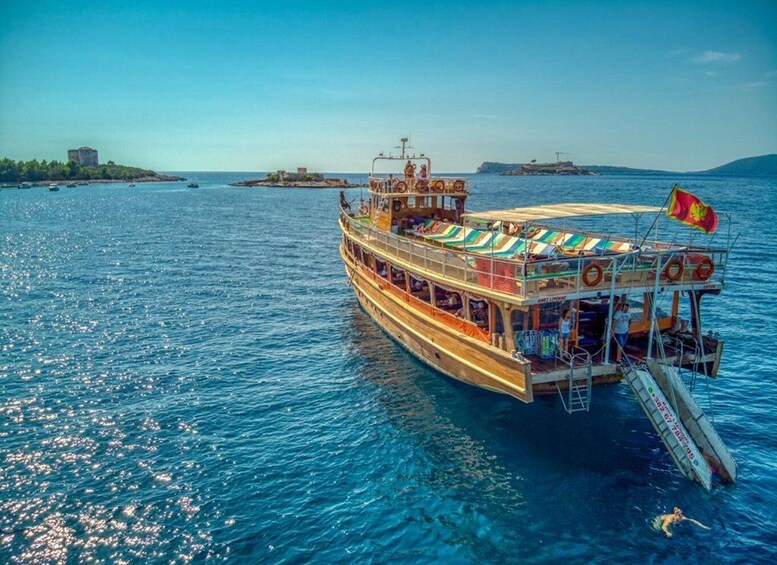 A large boat with a colorful deck and a flag, floating on a calm sea with clear blue water. 3