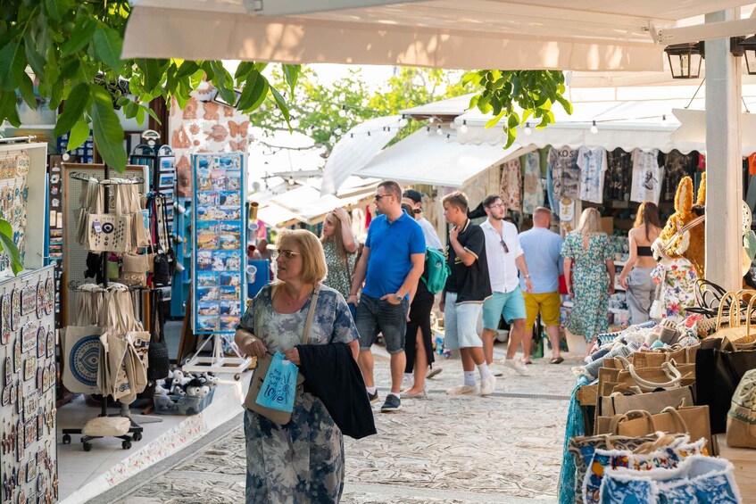 A bustling outdoor market with various stalls selling bags and accessories. 1