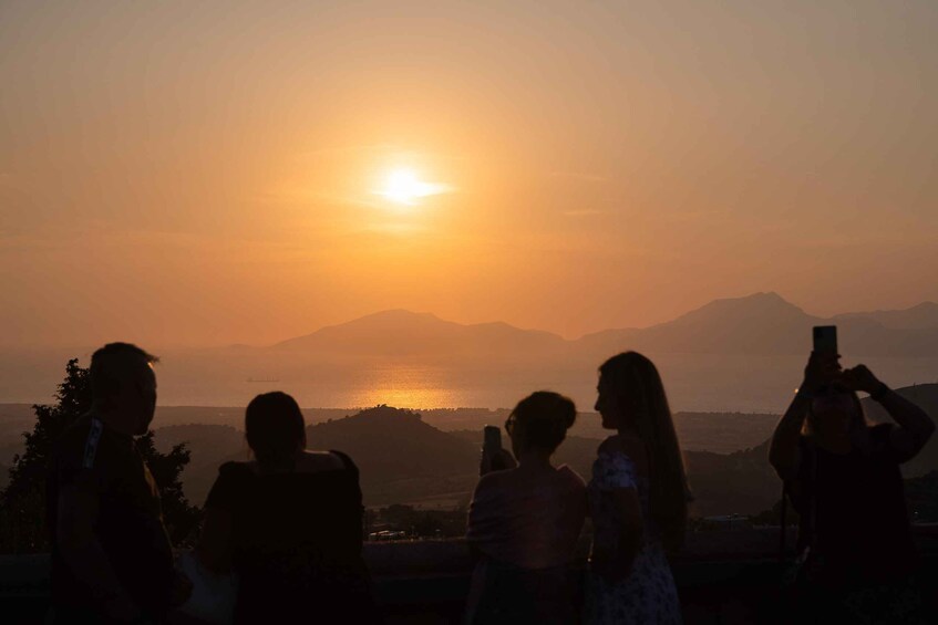 A group of people silhouetted against a sunset with mountains in the background. 5