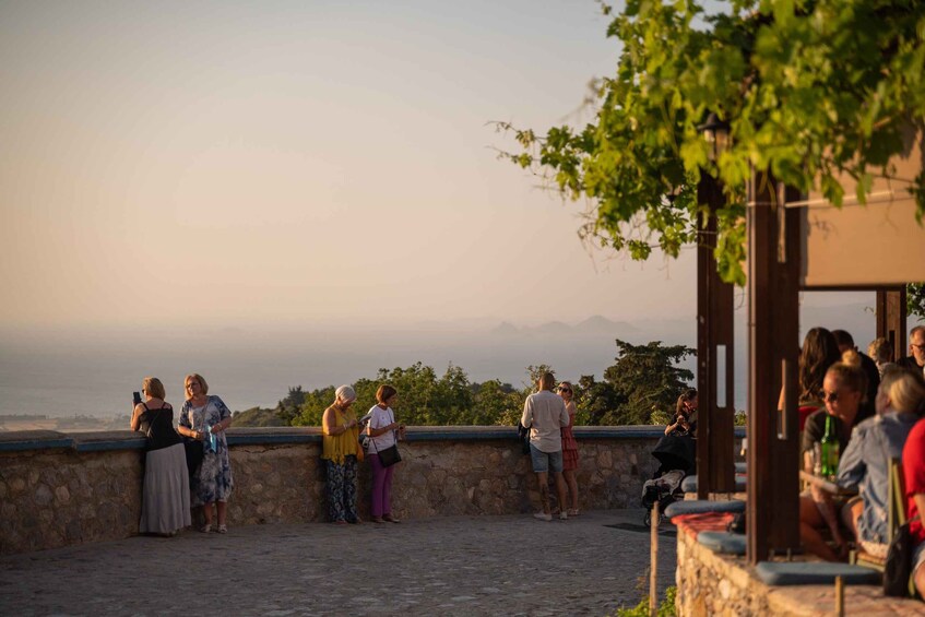 A group of people standing on a stone wall overlooking a scenic landscape with mountains in the distance. 2