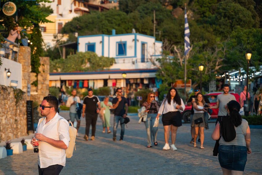 A busy street with pedestrians, a blue building, and trees. 3