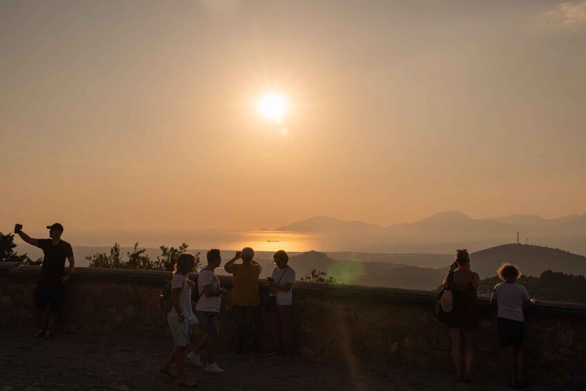 A group of people taking a sunset photo at a scenic overlook with mountains in the background. 5
