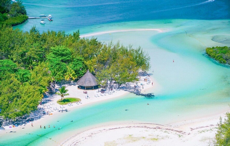 A tropical beach with clear turquoise waters, a thatched-roof hut, and lush greenery. 1