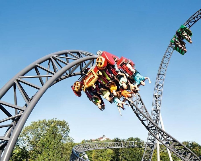 A roller coaster in motion with a clear sky and trees in the background. 3