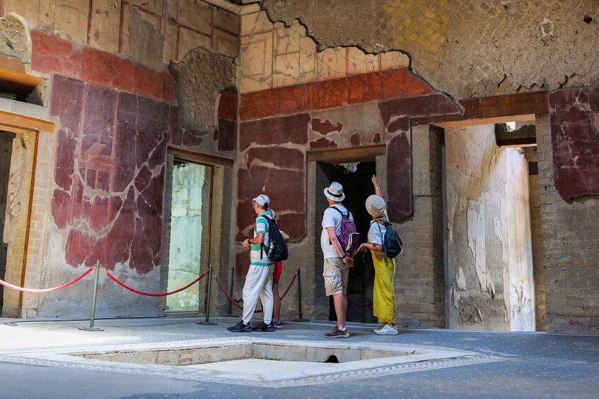 Tourists at an ancient ruin entrance with a red rope barrier. 5
