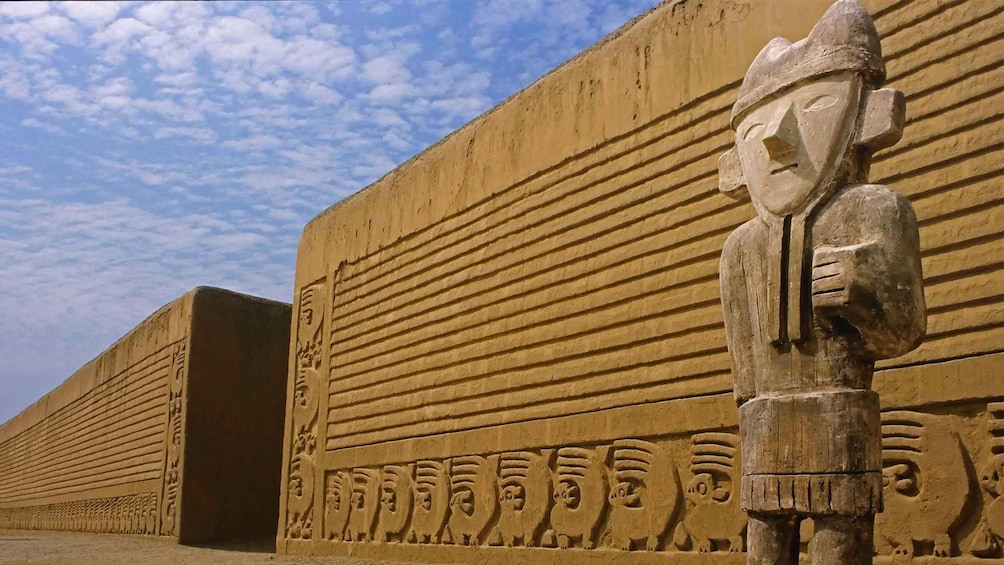 Un muro de piedra grande con líneas horizontales y una figura esculpida a la derecha. 1