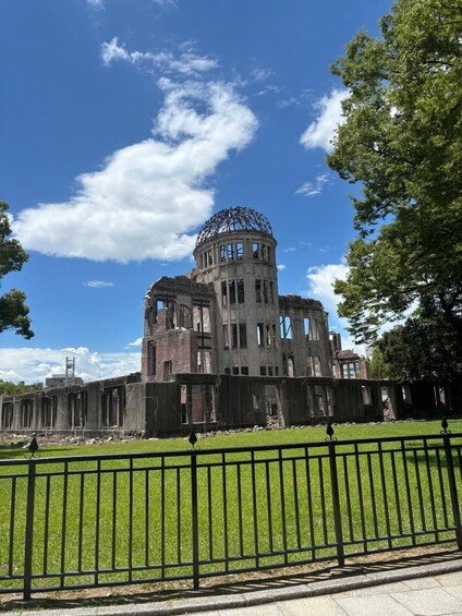 A large, circular building with a dome, surrounded by a green lawn and a black metal fence. 3