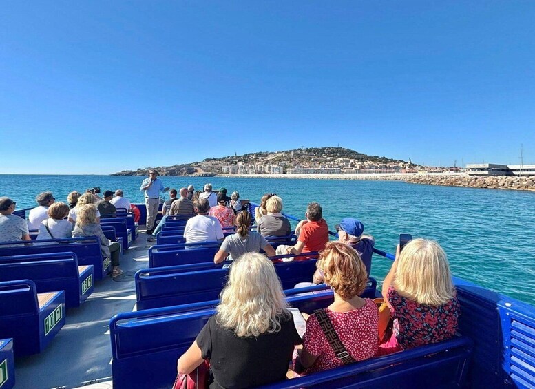 A group of people on a boat tour, with a coastal town in the background. 2