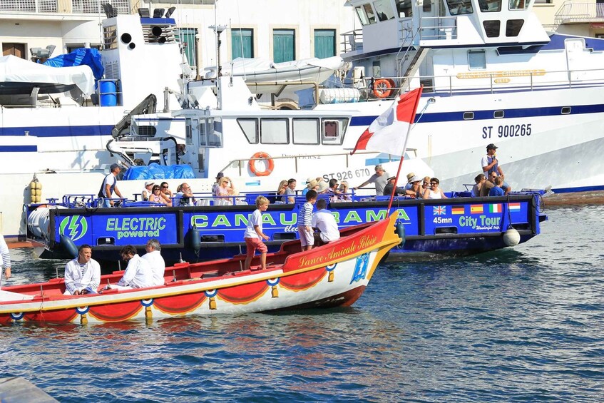 A colorful boat with people on board, docked at a marina with other boats. 4