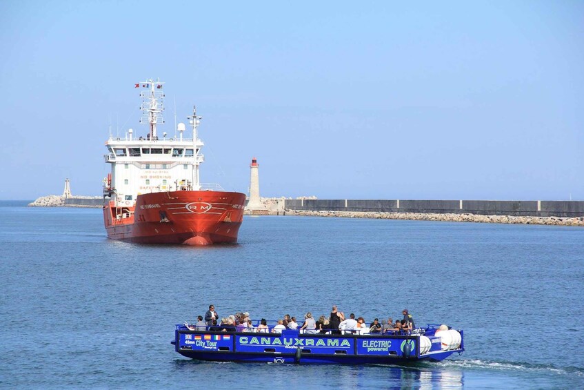 A red ship with a lighthouse in the background and a blue boat with passengers in the foreground. 5