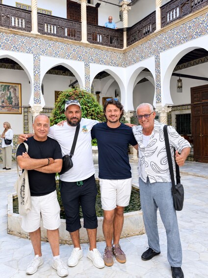 A group of people standing in an architectural courtyard with arches and patterned tiles. 2
