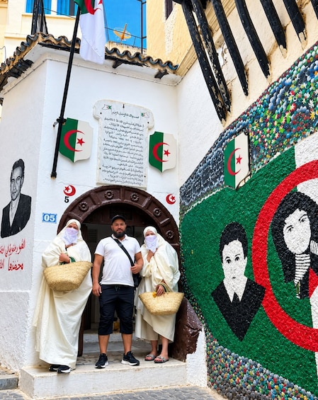 A building facade with flags, a mural, and a plaque. 1