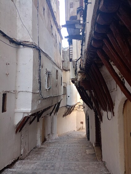 A narrow alleyway with cobblestone pavement, white walls, and a wooden door at the end. 5
