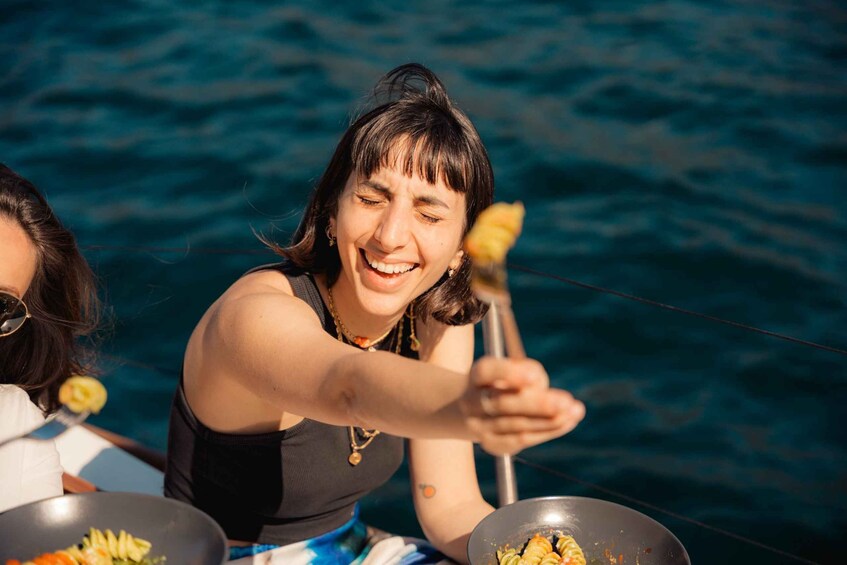 A person cooking outdoors, possibly on a boat, with a pan on a table. 2
