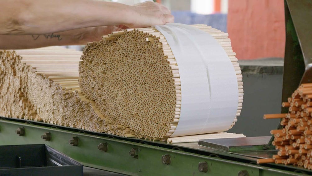 A person handling a large roll of material, possibly paper or fabric, on a conveyor belt. 3