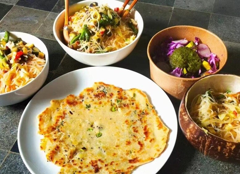 A variety of Asian dishes including noodles, a rolled omelette, and a salad with purple cabbage. 3