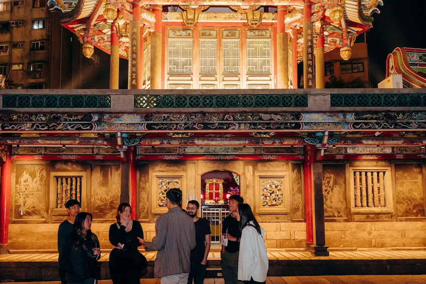 A traditional Chinese building with ornate decorations and a group of people standing in front. 3