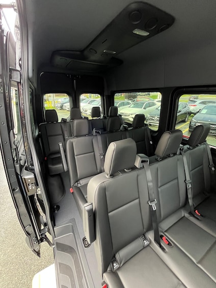 A vehicle interior with multiple rows of seats and a rearview mirror. 2