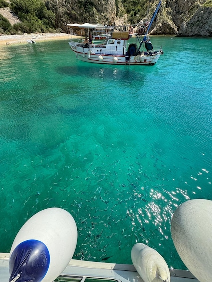 A boat on a turquoise sea with rocky cliffs in the background. 4