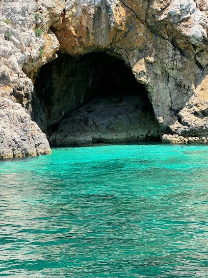 A rocky cave entrance with turquoise water. 2