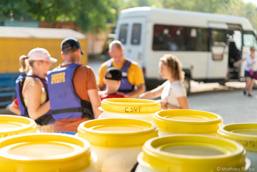 People gathered around yellow containers with 'CSV' written on them, a bus in the background, and a person walking away. 4