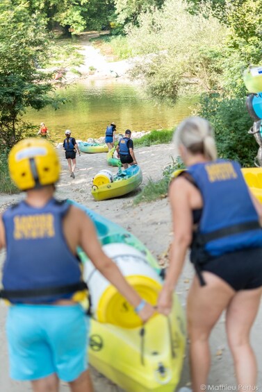 People preparing kayaks by a river. 3