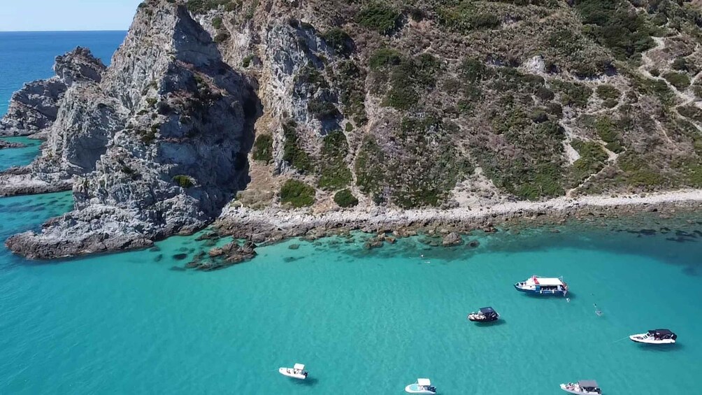 A coastal landscape with rocky cliffs and clear turquoise waters. 5