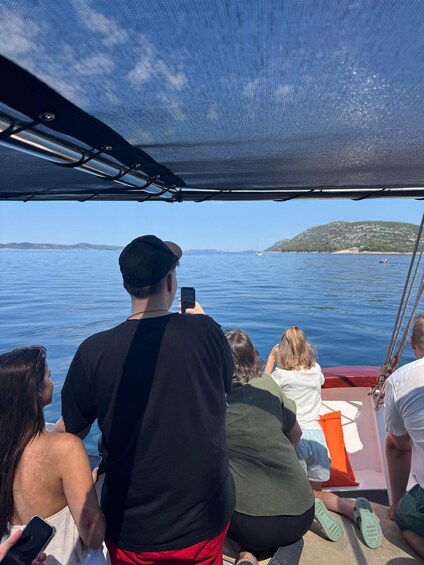 A group of people on a boat, facing a calm sea with a distant island. 2