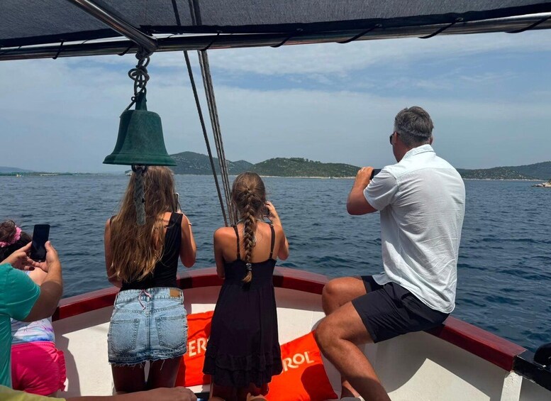 A boat with people on board, a woman in a green hat, and a man taking a photo. 3