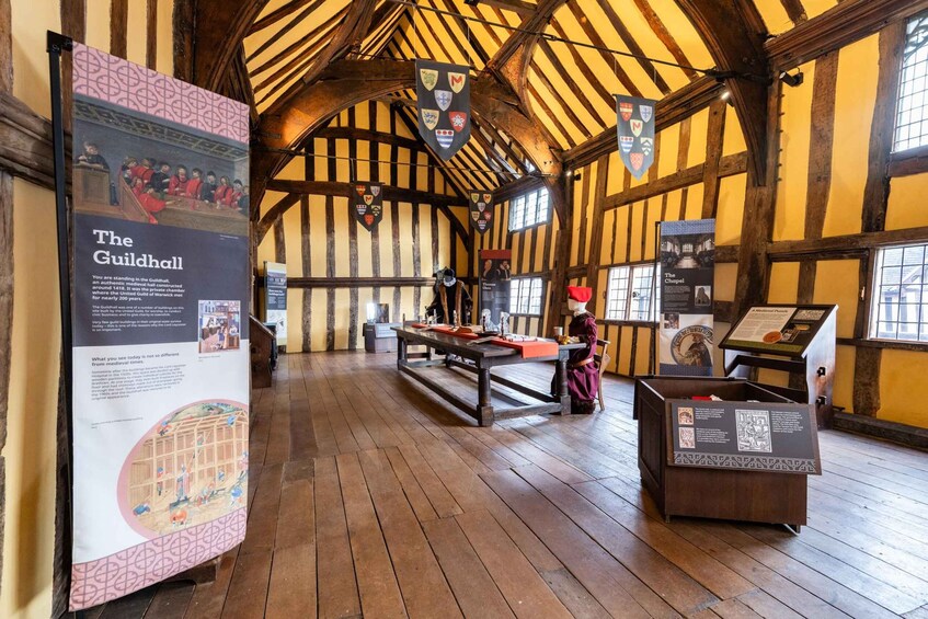 A medieval hall with wooden beams, a long table, and informational displays. 3