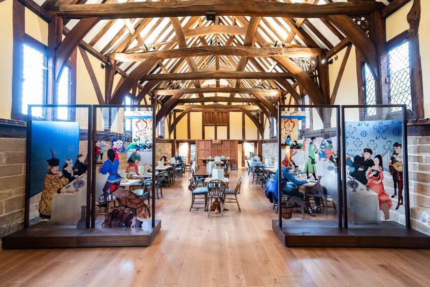 A spacious room with wooden beams and a high ceiling, featuring a central table surrounded by chairs. 5