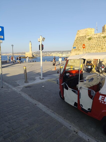 A coastal road with a red and white vehicle, a lighthouse, and a stone wall in the background. 5