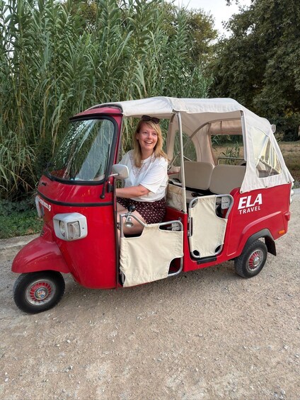 A red and white car with a canopy, parked on a dirt road with greenery in the background. 5