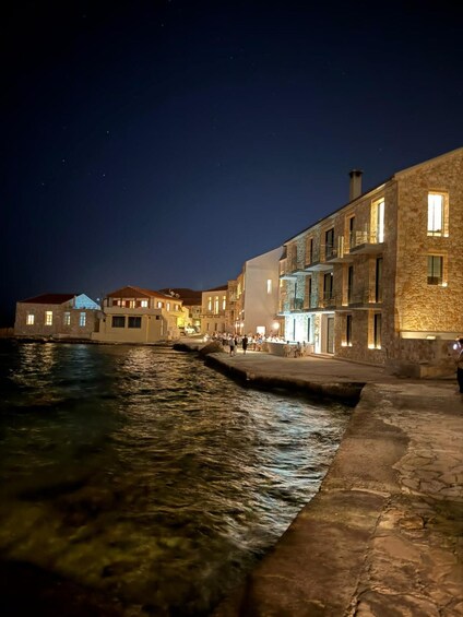 A waterfront street at night with illuminated buildings and a calm river. 2